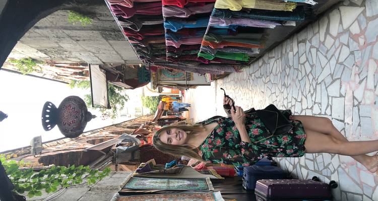 Un voyageur sourit en parcourant une ruelle de marché étroite bordée de foulards colorés à Istanbul.