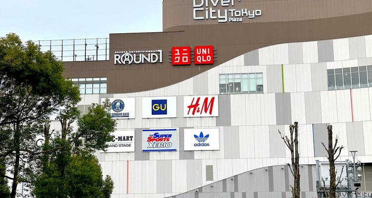 Gevel van het winkelcentrum DiverCity Tokyo Plaza met veel internationale merk-logo's.
