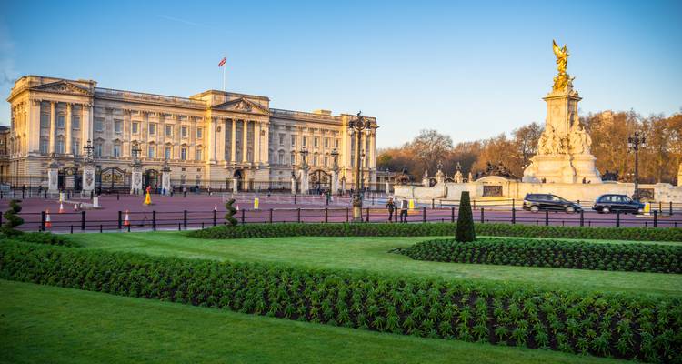Le Palais de Buckingham et le Mémorial Victoria encadrés par des pelouses impeccablement entretenues sous un ciel matinal dégagé.