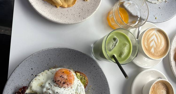 Table de petit-déjeuner avec tartine à l'œuf frit, pâtisseries, café, jus et latte matcha