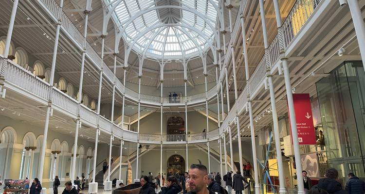 Grand atrium aux vitres du Musée national d'Écosse rempli de visiteurs explorant des galeries à plusieurs niveaux