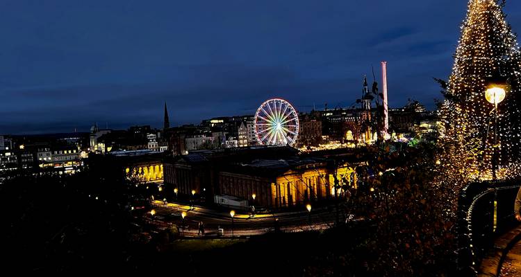Vue panoramique nocturne de la fête foraine festive d'Édimbourg avec une grande roue illuminée et des bâtiments classiques éclairés