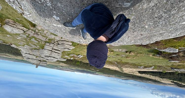 Niño sentado en una roca de granito con vistas a extensos páramos ondulantes y formaciones rocosas.
