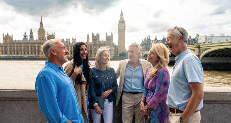 Group of friends laughing together on the Thames embankment with Big Ben and Parliament behind.