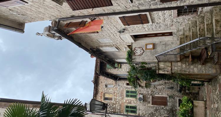 Encantador callejón de piedra estrecho con bandera y ventanas con contraventanas en un pueblo antiguo