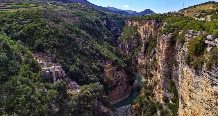 Deep limestone canyon with sheer cliffs and emerald river far below.