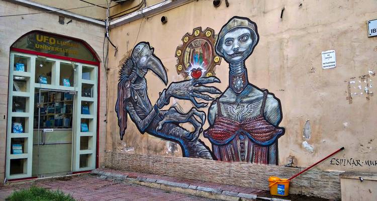 Colorful surreal mural on an urban wall beside a doorway in a city alley.
