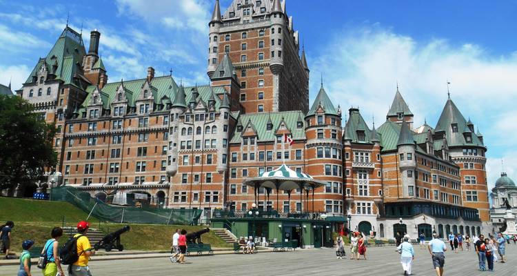 L'hôtel emblématique Chateau Frontenac dominant une promenade en bois animée par les touristes sous un beau jour d'été.
