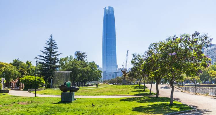 La haute tour en verre du Centre Costanera s'élève au-dessus d'un parc urbain verdoyant par une journée ensoleillée.
