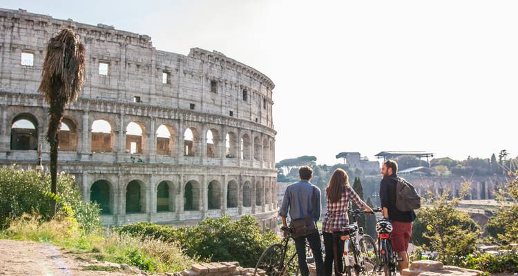 Trois cyclistes font une pause pour admirer les ruines du Colosseum par une journée ensoleillée.