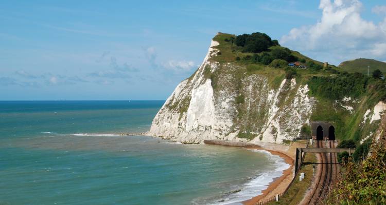 White chalk cliff face with twin railway tunnels and turquoise sea below.