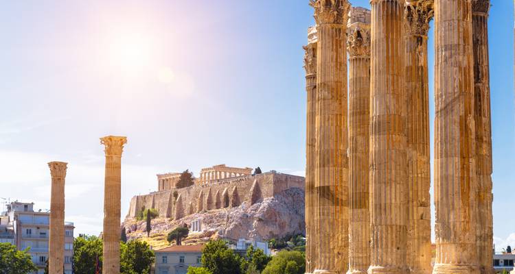 Tall Corinthian columns of the Temple of Olympian Zeus with the Acropolis in the sun-drenched distance.