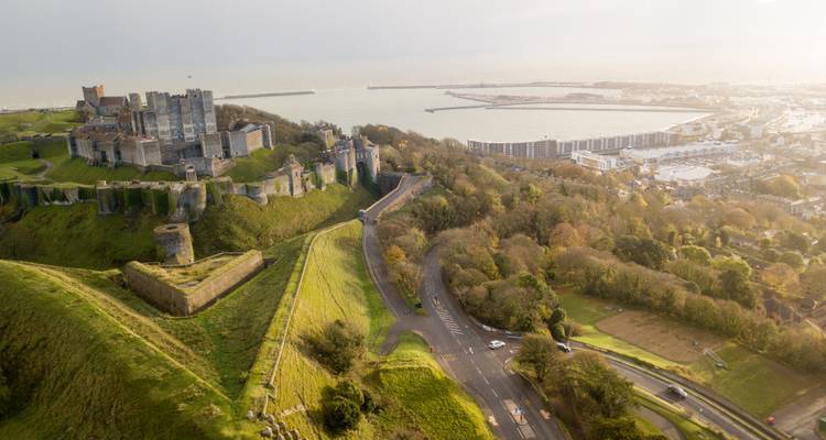 Vue aérienne du château médiéval de Douvres perché sur les falaises verdoyantes surplombant le port animé