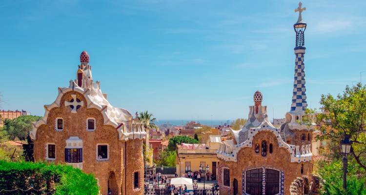 Les bâtiments aux styles de pain d'épices de Gaudí et la tour aux carreaux bleus du Parc Güell encadrés par un ciel printanier éclatant.