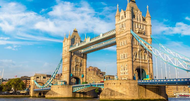 Clear blue sky frames Tower Bridge with its pale stone towers and vivid blue suspension elements.