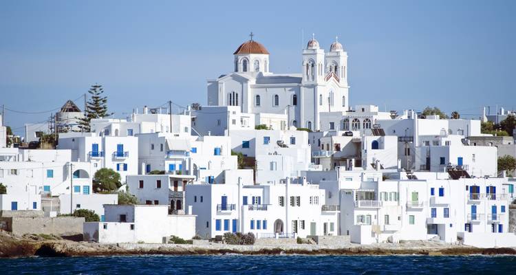Seaside whitewashed village and church on Paros island viewed from across the water.