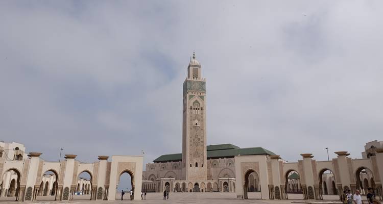 Vista amplia del patio de la Mezquita Hassan II con su imponente minarete bajo un cielo brumoso.