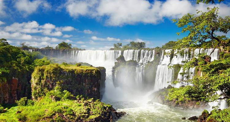 Vista panorámica de las Cataratas del Iguazú rodeadas de acantilados verdes bajo un cielo brillante