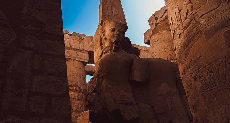 Enorm zittend farao-beeld tussen hoge, met hiëroglieven bedekte zuilen in een oud Egyptische tempel