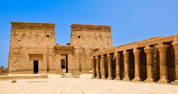 Zonnig binnenplein van de Philae Tempel met tweelingpylonen en een zuilengalerij onder een hemelsblauw