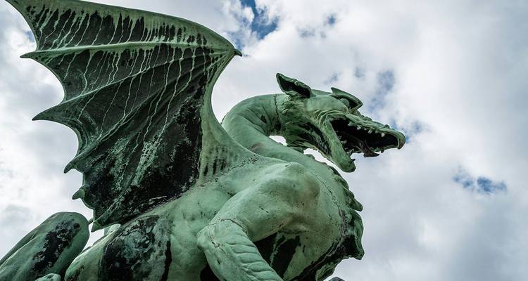 Close-up of the famous green dragon statue on Dragon Bridge against cloudy sky in Ljubljana.