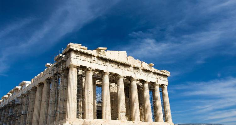 The Parthenon temple under blue skies with scaffolding visible on one side.