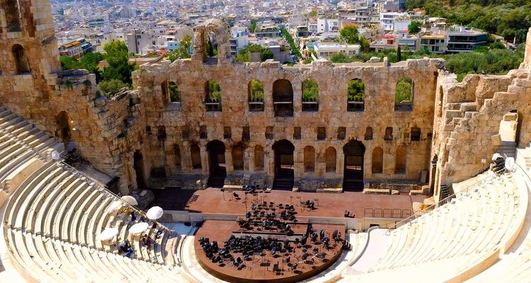 Interior view of the ancient Odeon of Herodes Atticus amphitheater with cityscape behind.