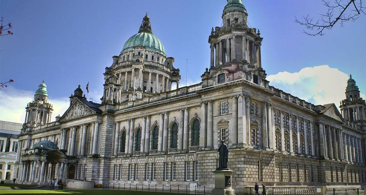 Elegant neoclassical city hall with green domes and statues under clear blue sky