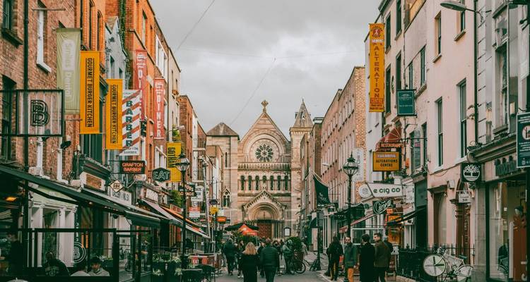 Busy pedestrian shopping street lined with colorful signs and a church at the far end