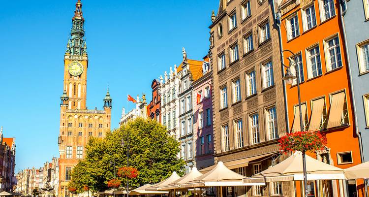 Clock tower and ornate facades lining a sunny pedestrian street in a Baltic seaport