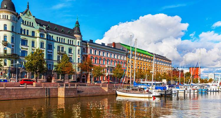 Colorful historic waterfront buildings reflected in harbor waters beneath puffy clouds