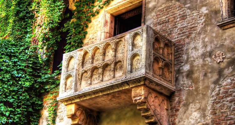 Ivy-clad Juliet’s stone balcony projecting from weathered brick wall in Verona