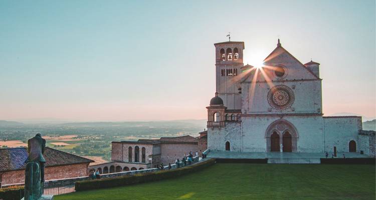 Basilica of Saint Francis of Assisi glowing in warm light with sunburst behind its tower