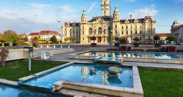 L'élégant hôtel de ville de Györ se reflétant dans les fontaines modernes sous un ciel bleu