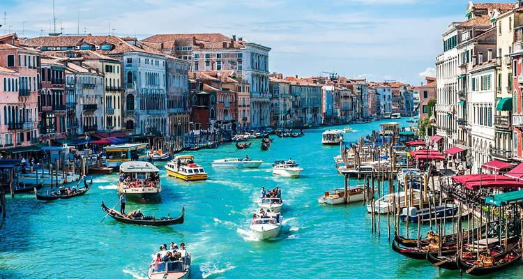 Der belebte Große Kanal in Venedig, gefüllt mit Gondeln und Motorbooten unter blauem Himmel