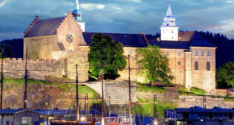 Akershus Fortress in Oslo verlicht boven de haven bij schemering.