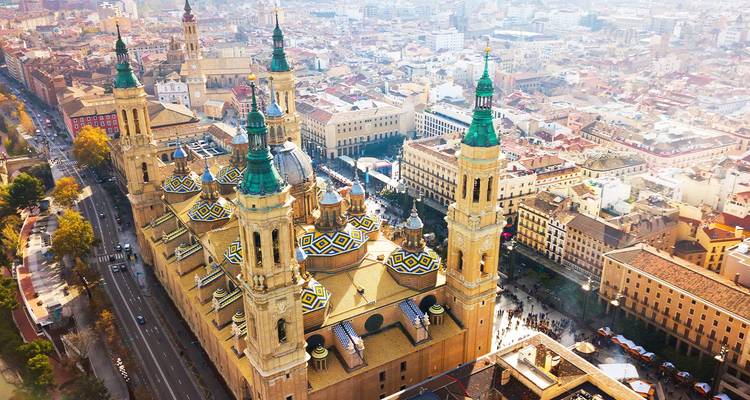 Vogelperspektive der großartigen Basilica del Pilar von Zaragoza mit ihren farbenfrohen gekachelten Kuppeln neben dem Fluss Ebro.