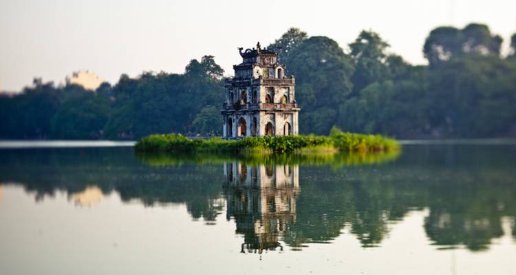 The small Turtle Tower sits on an island reflected in the calm waters of Hoan Kiem Lake.