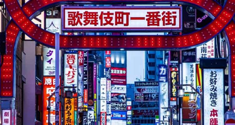 Neon-lit Kabukicho Ichiban-gai gate and surrounding billboards glow in Tokyo’s entertainment district at night.