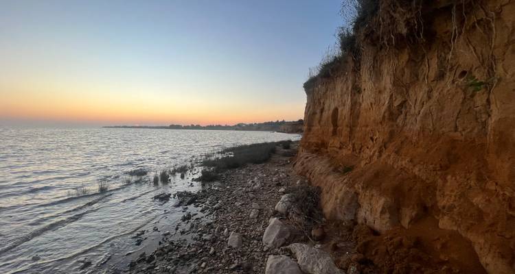 Falaise côtière érodée et rivage de galets à la lumière douce du coucher de soleil