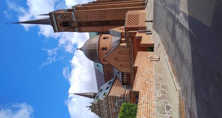 Vue panoramique des deux tours et dômes de la cathédrale de Roskilde s'élevant au-dessus des chapelles en briques sous des ciels dégagés