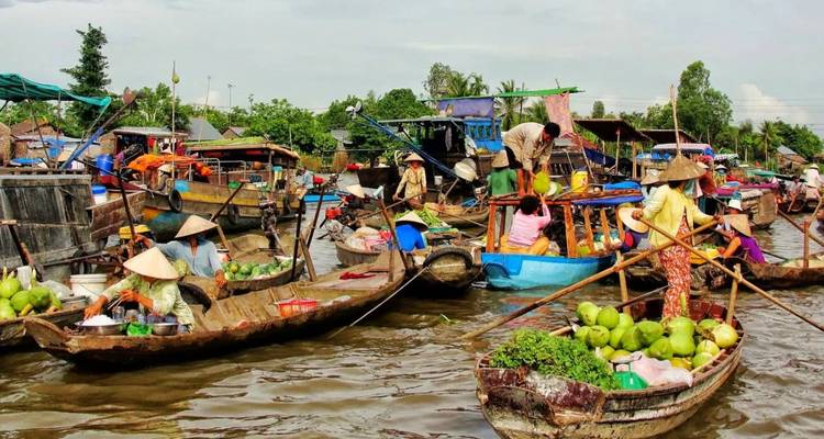 Geschäftiger Schwimmmarkt am Mekong-Fluss mit Verkäufern in Holzbooten, die Produkte handeln.