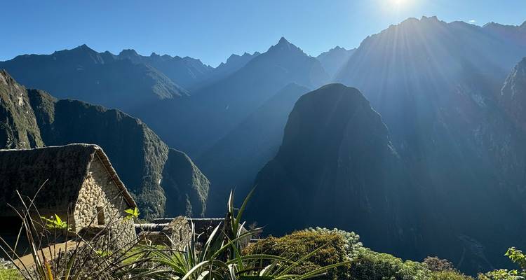 Morgenlicht über den dramatischen Bergen und Ruinen von Machu Picchu mit Sonnenstrahlen, die über das Tal scheinen.