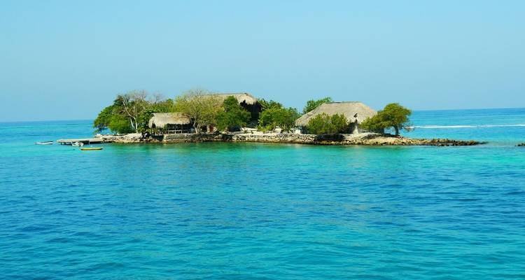 Tiny thatched-roof resort island surrounded by clear Caribbean waters