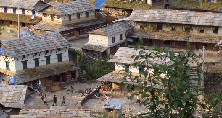 Vue aérienne d'une place de village himalayenne pavée de pierre avec des habitants et des toits en terrasse.