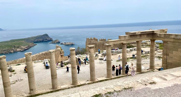 Ancient colonnade overlooking the Aegean Sea with many visitors walking around