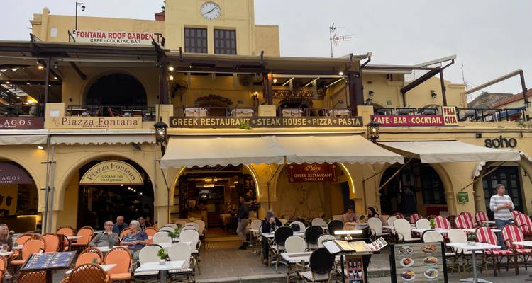 Busy restaurant frontage with outdoor seating, menus and illuminated signs
