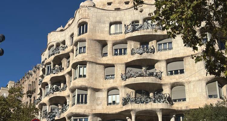 Les balcons de pierre courbes et la façade ondulante de la Casa Milà (La Pedrera) illuminés par le soleil de l'après-midi.