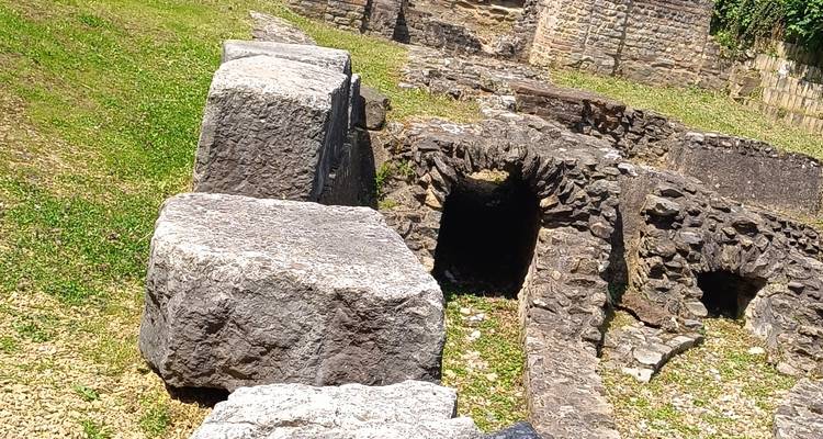 De grands blocs de pierre rectangulaires et un petit tunnel voûté dans des ruines anciennes baignées de lumière solaire éclatante