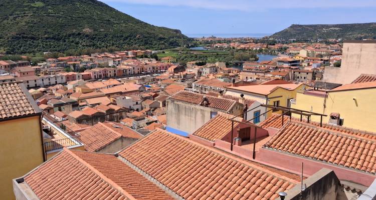 Rooftop panorama of terracotta tiles overlooking river valley and hills.